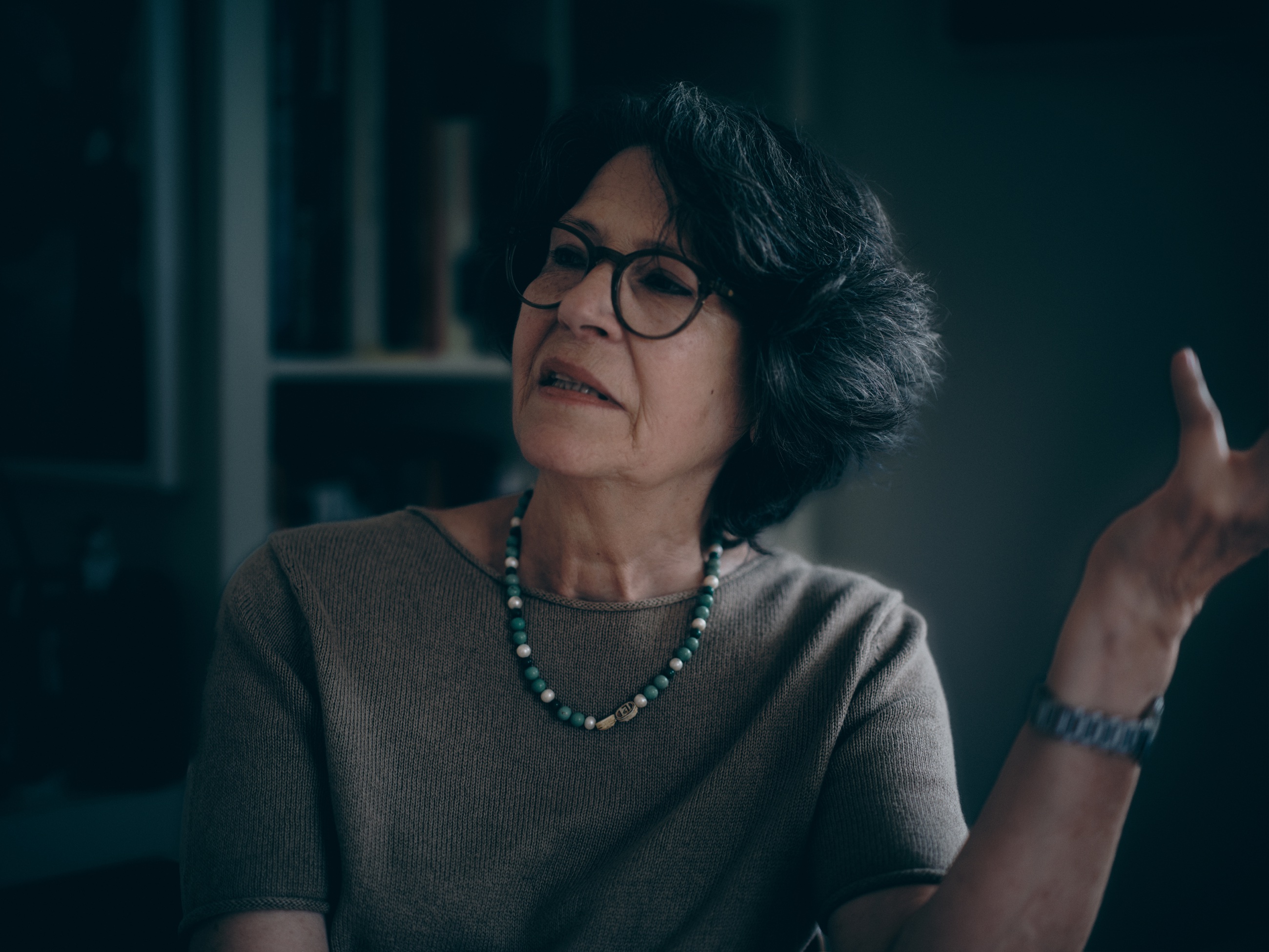 Maria während eines Gesprächs, eine Hand offen erhoben.